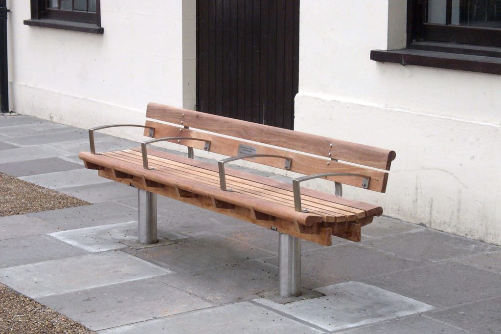Long bench with multiple arm rests to prevent anyone laying down on it. 