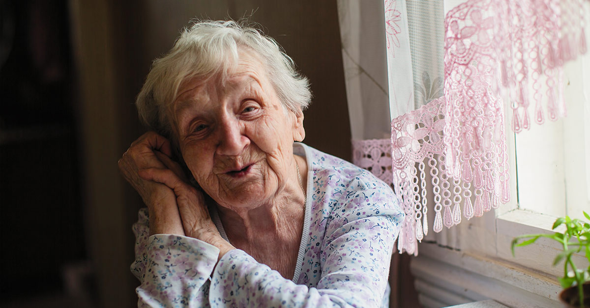 an elderly woman smiling by a window