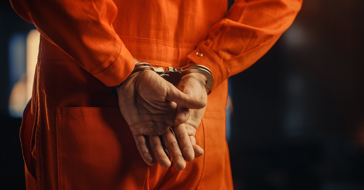 prisoner wearing orange jumpsuit handcuffed with hands behind back