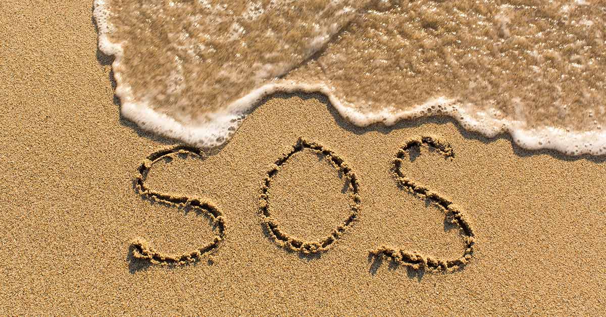 SOS written in sand on a beach
